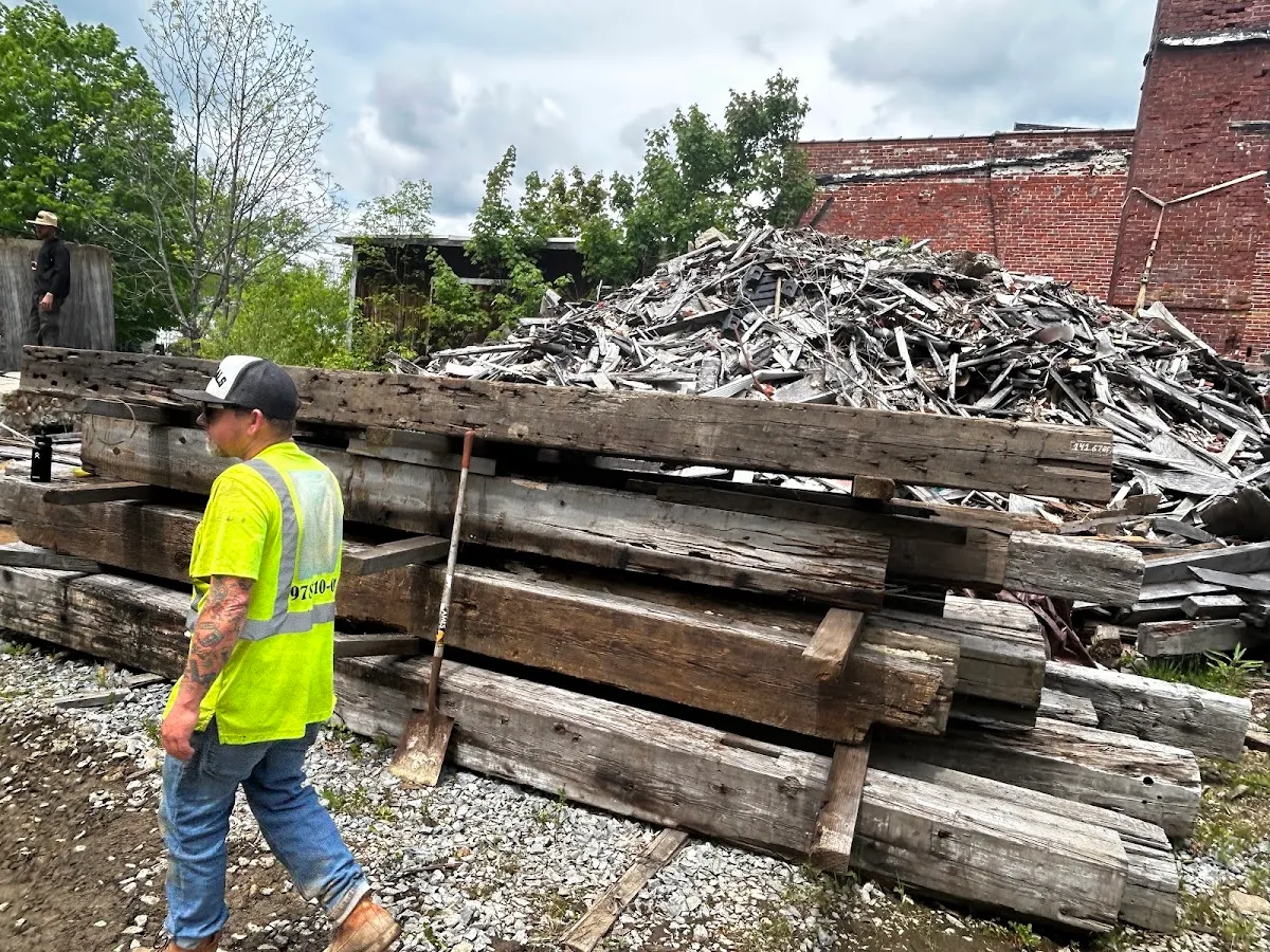 Reclaimed beams stacked outdoors beside a salvage yard