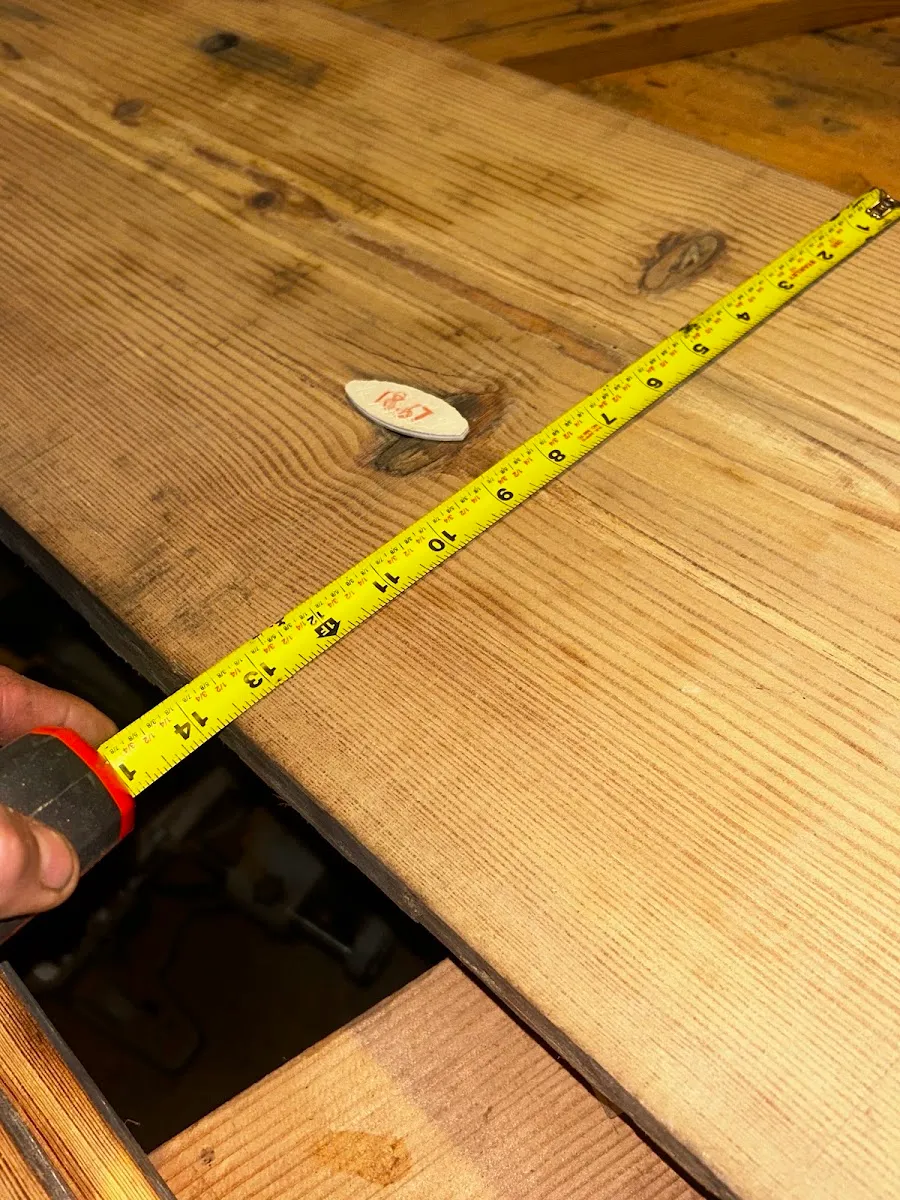 Finished heart pine boards checked with a tape measure, with the grain visible across the surface