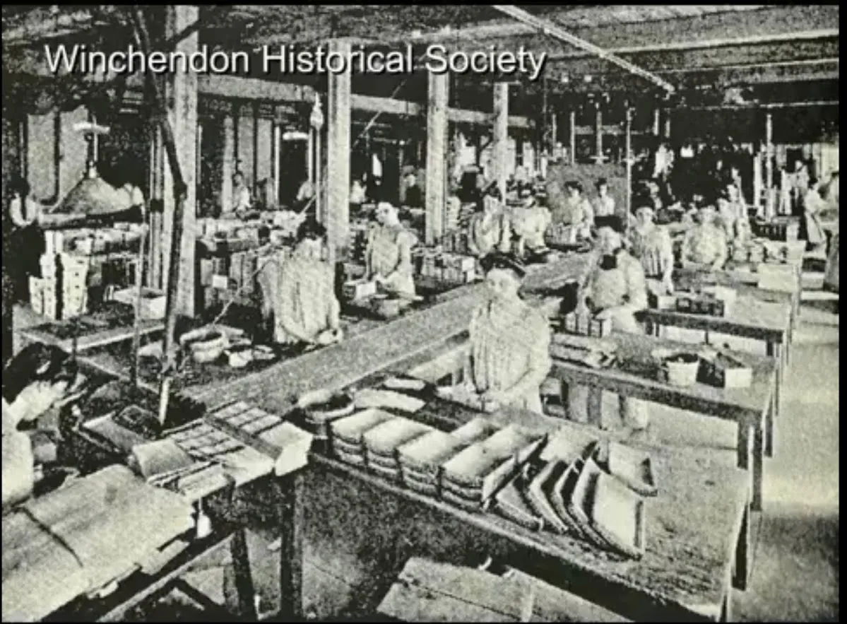 Historic black and white photograph of toy factory workers at tables