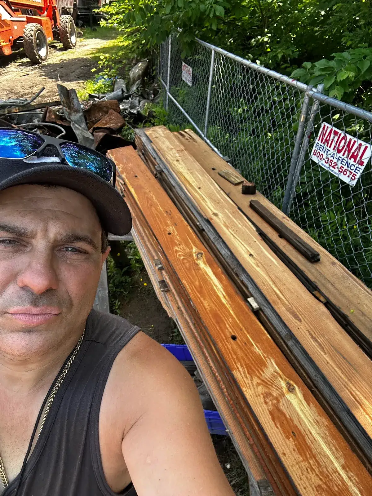 Salvage worker beside reclaimed boards laid out near a fence
