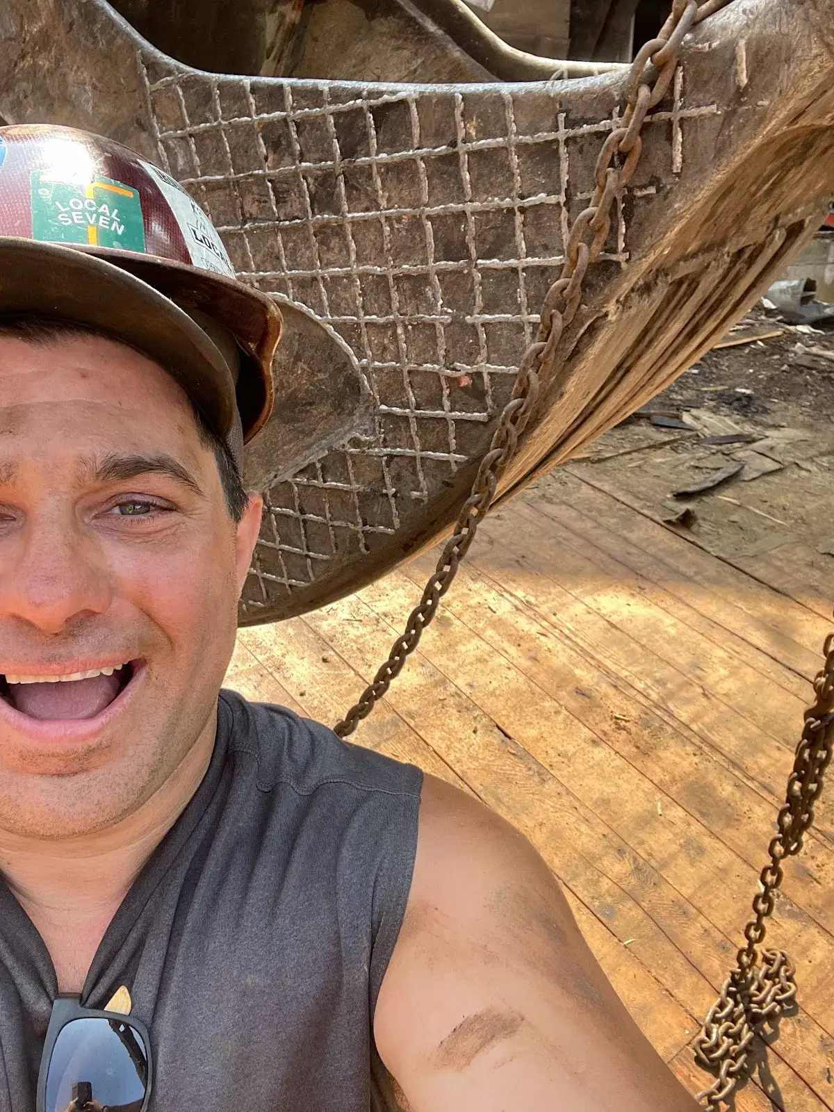 Salvage worker standing beside an old wood floor and heavy steel bucket