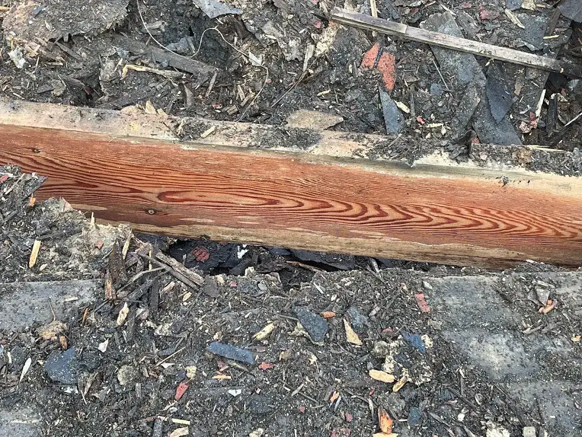 Close view of a dark weathered beam with a yellow tape measure