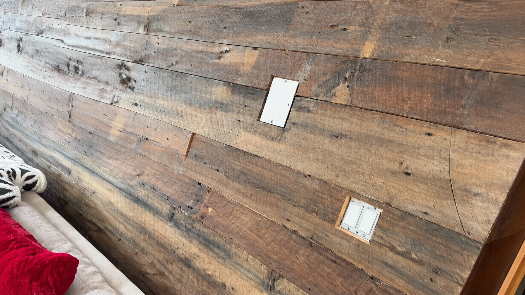 Angled view of the 1809 chestnut, wormy chestnut and pine focal wall, with the room's seating at left, wall outlets, and custom vertical grain heart pine doorway trim at right